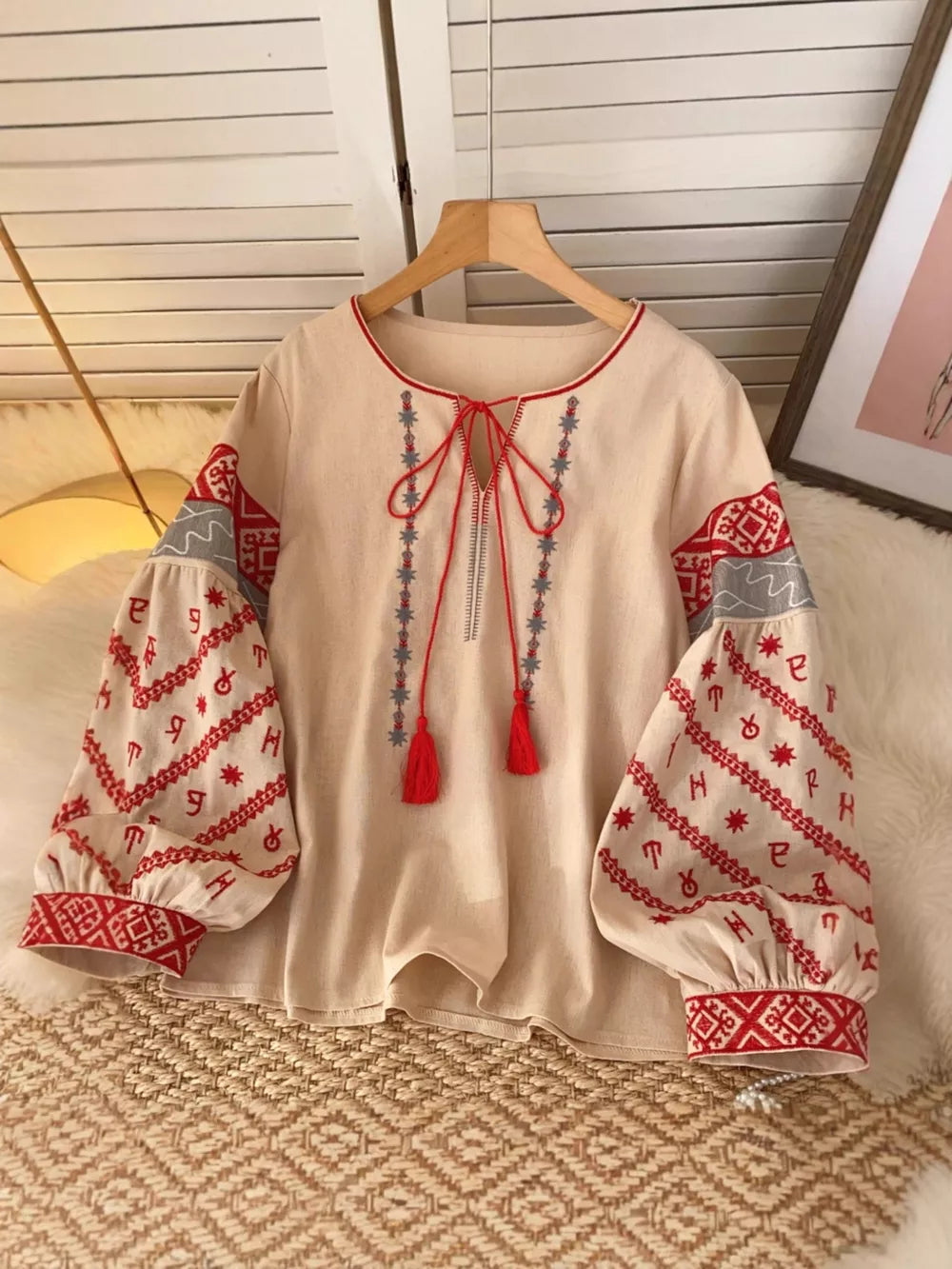 Apricot tie neck shirt with folk embroidery on sleeves and neckline, red tassels.