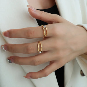Gold sculptural ring with pearl accent, featuring an open oval design.
