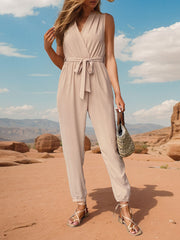 Tan draped wrap jumpsuit with V-neck, belted waist, and jogger cuffs.