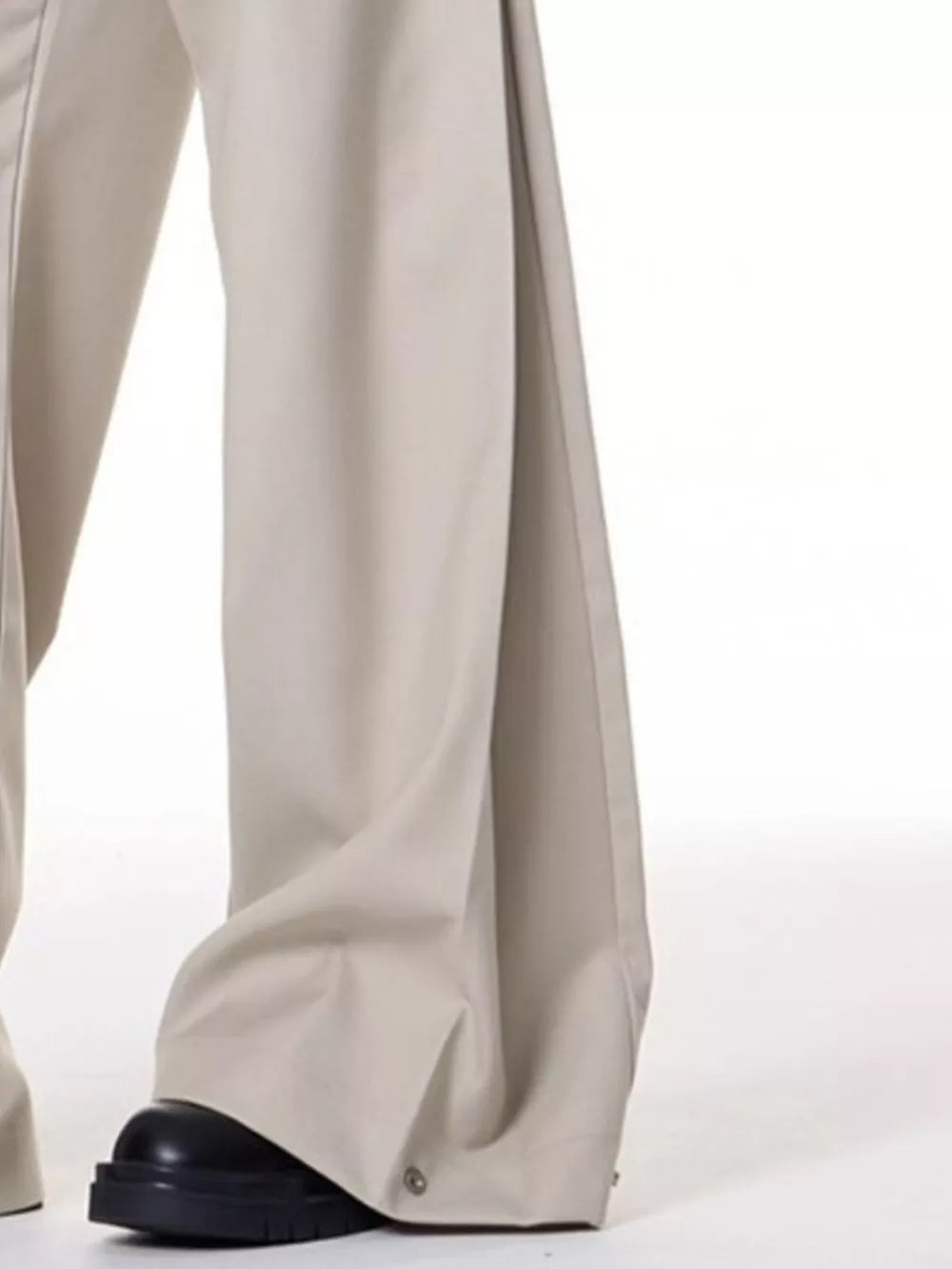 Men's beige wide-leg sweatpants with snap closure detail at the hem.