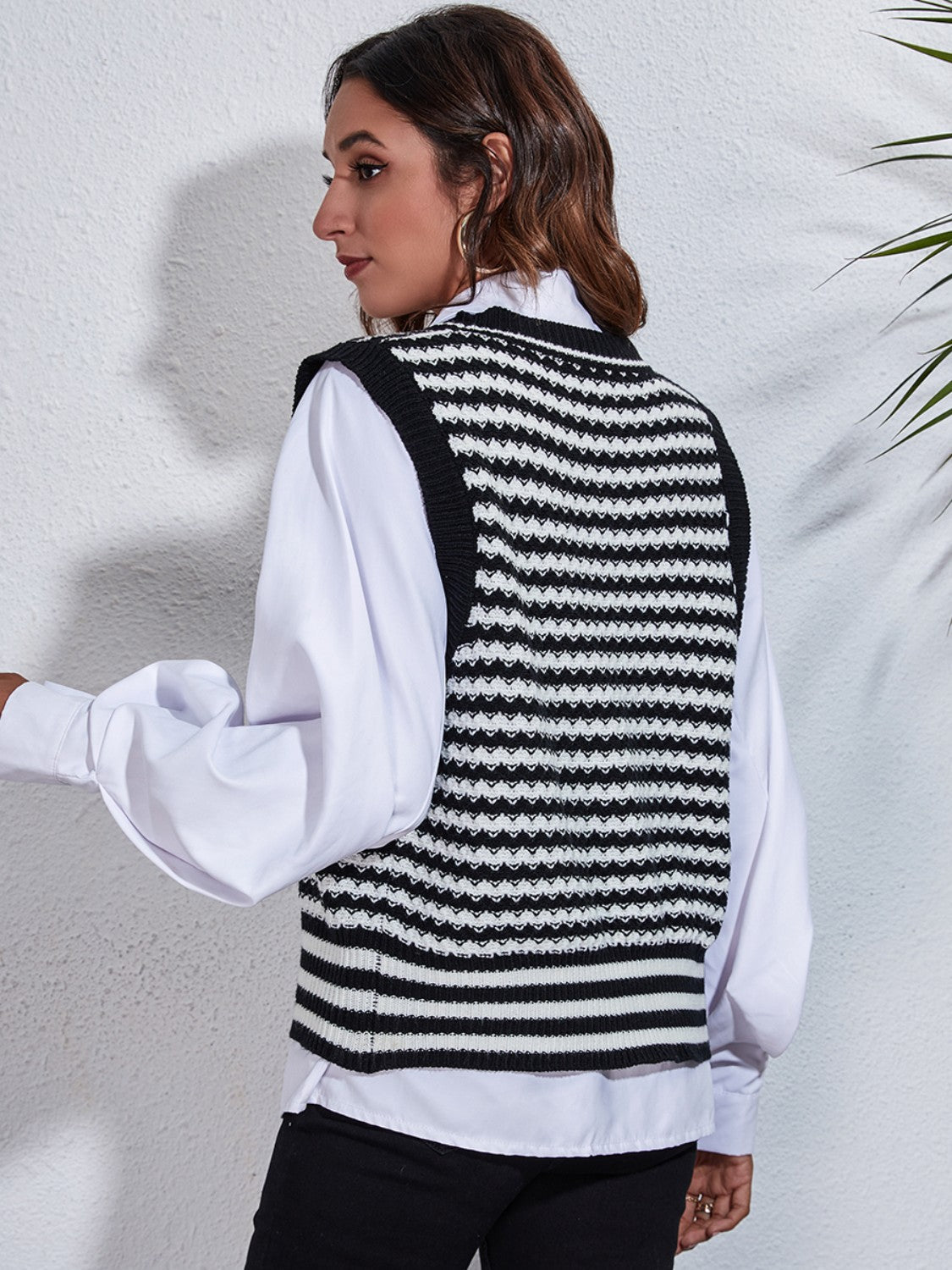 Black and white striped knit vest with a double-breasted detail, worn over a white shirt.