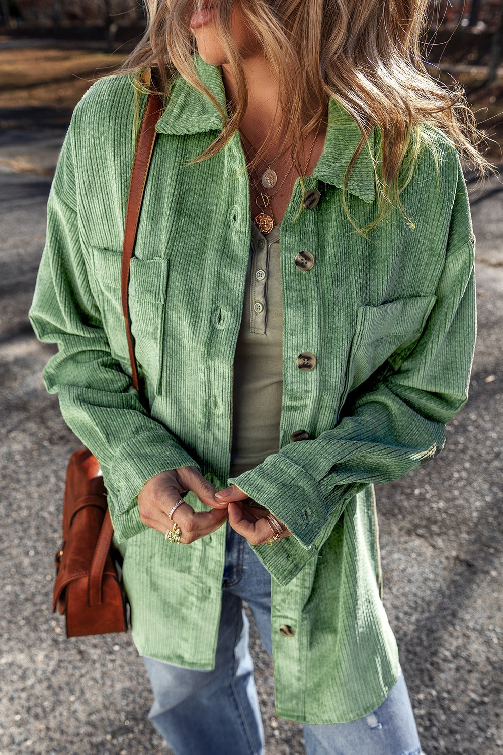 Green corduroy overshirt with button cuffs and chest pockets, styled with jeans.
