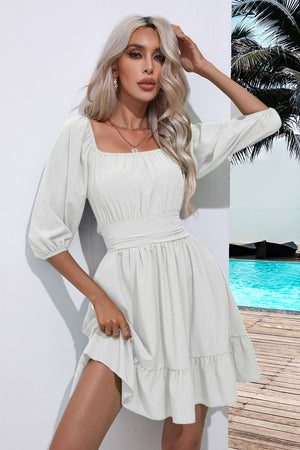 White mini dress with square neckline, puff sleeves, cinched waist, and ruffled hem.
