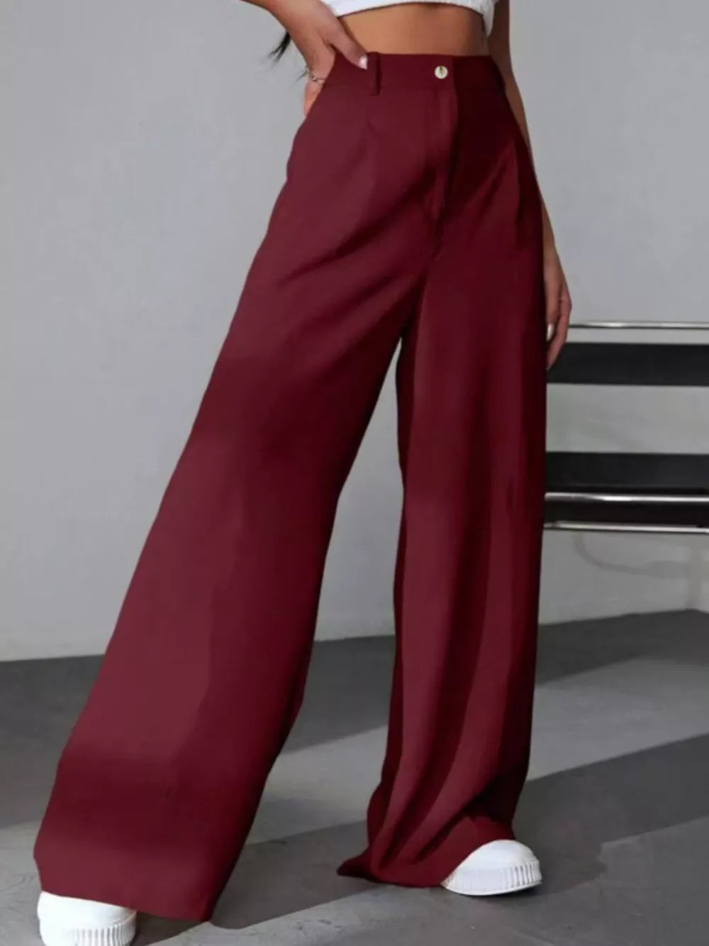 Burgundy high-waisted pleated wide-leg maternity trousers with button detail.