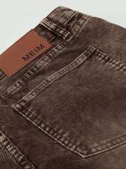 Brown corduroy joggers with a leather brand patch and visible stitching detail.