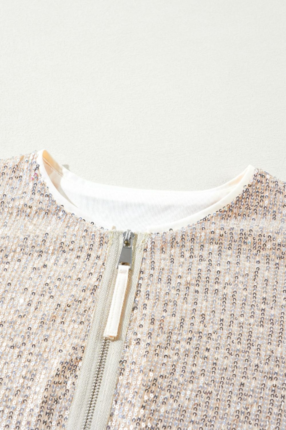Sequin bomber jacket in cream with ribbed trim and silver zipper detail.