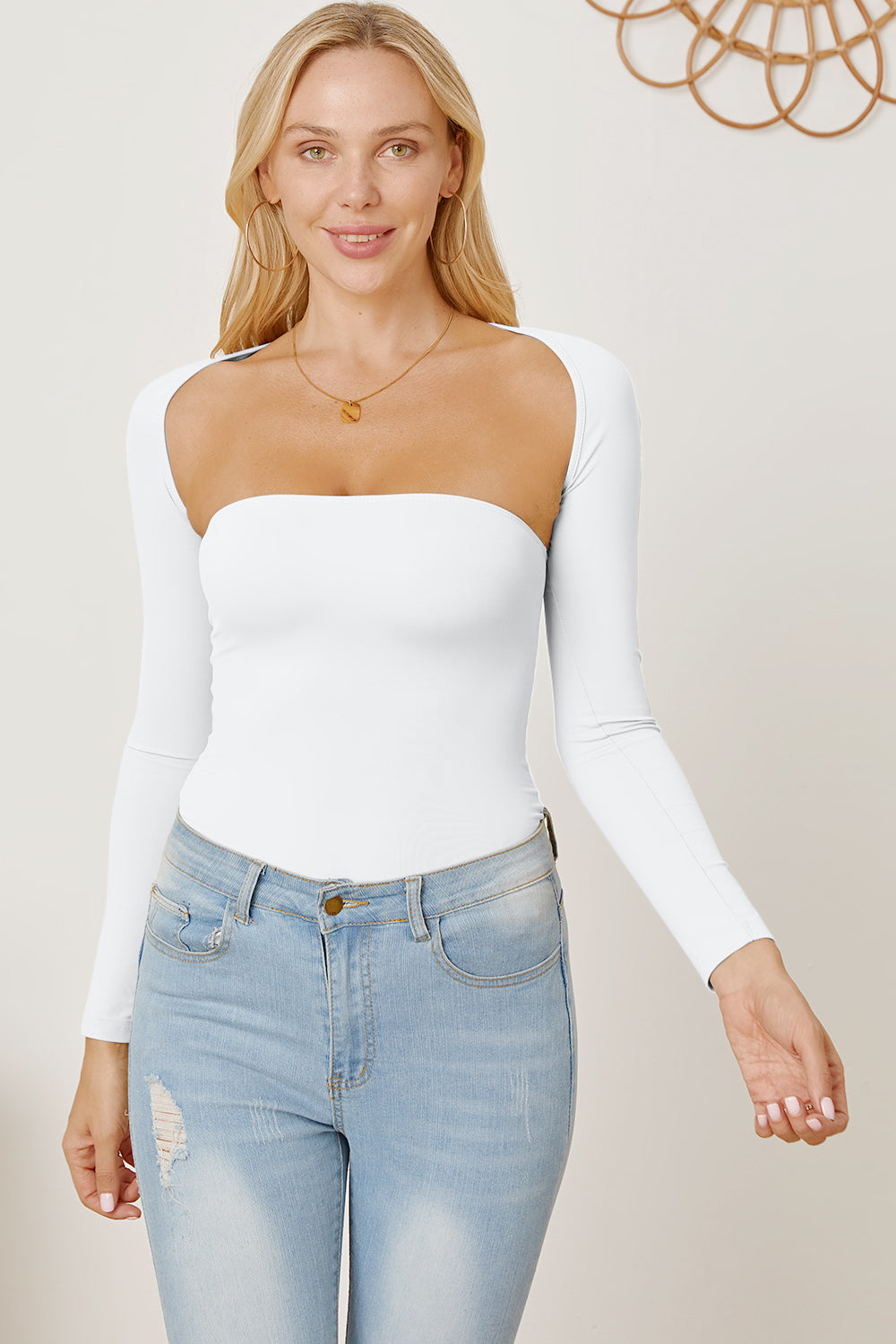 White long sleeve bodysuit with square neckline and open back detail, styled with jeans.