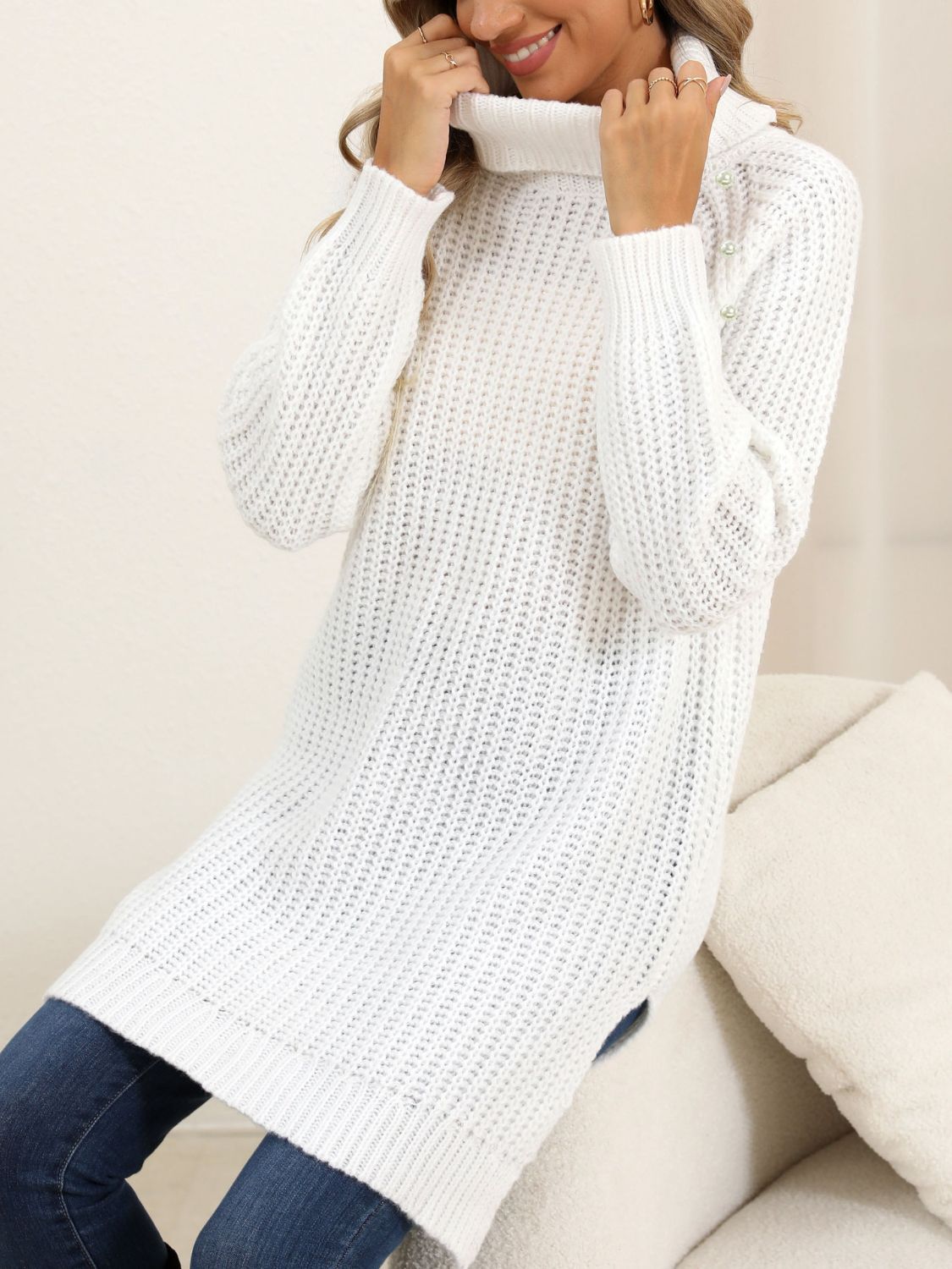 White ribbed turtleneck tunic with pearl embellishments on the shoulder.