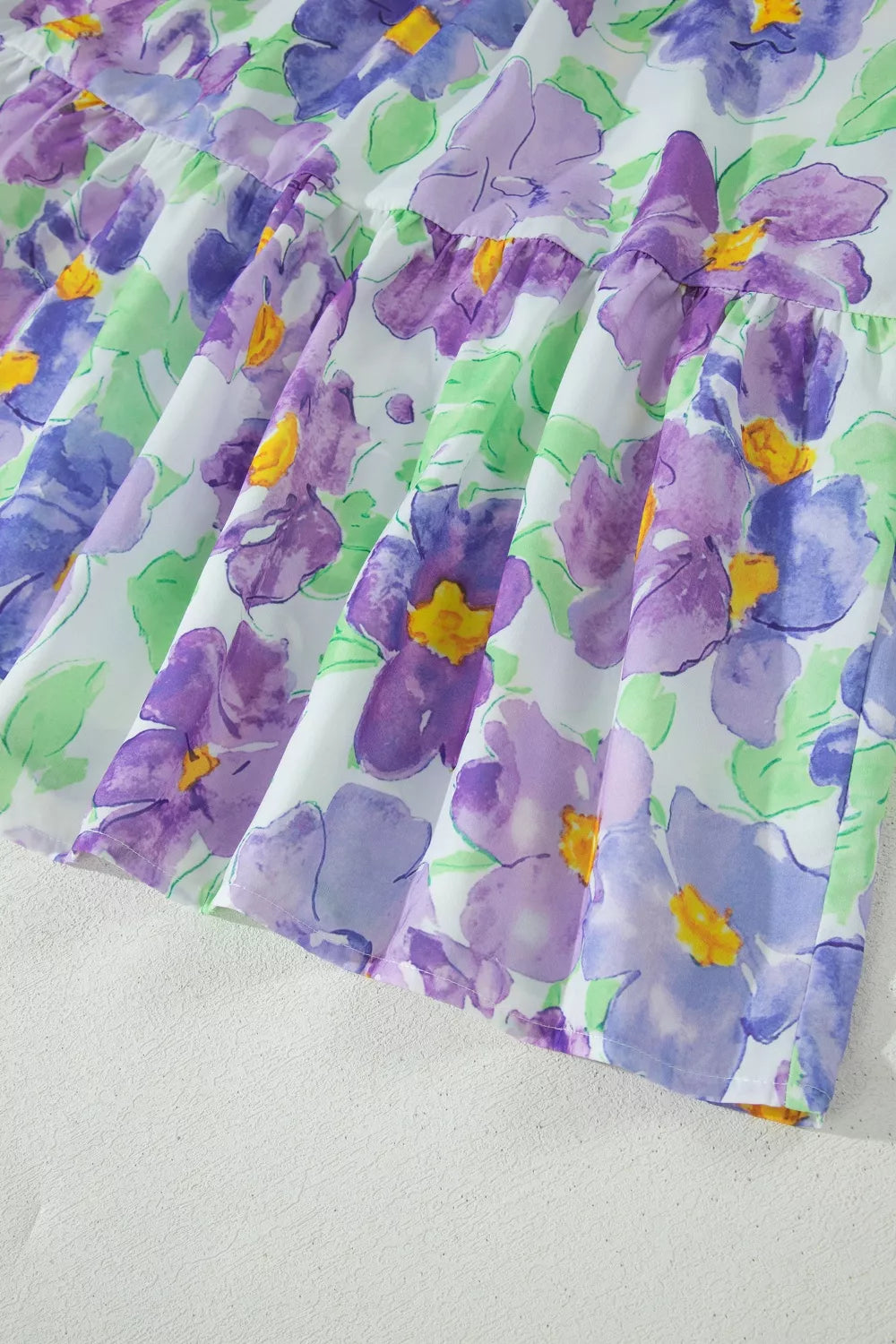 Vibrant floral mini dress with tiered ruffles and purple watercolor flowers.