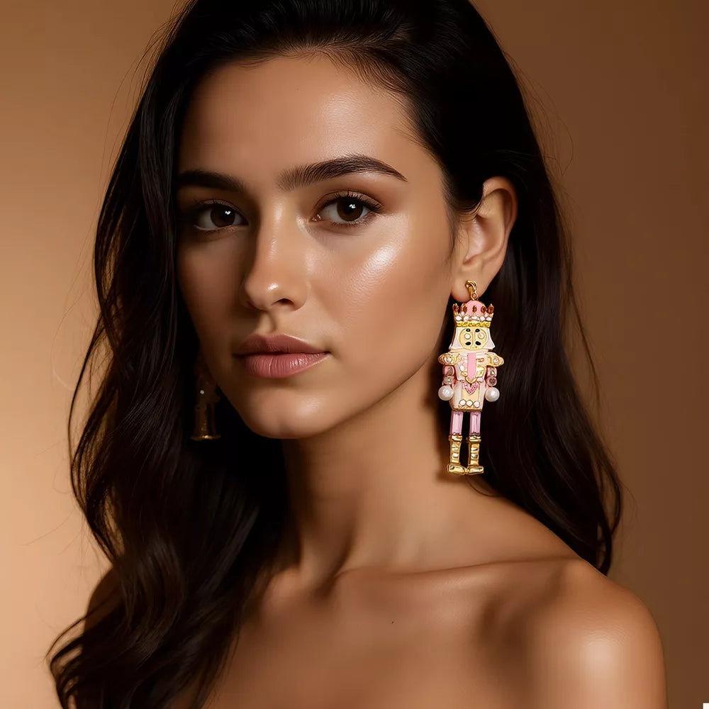 Blush pink nutcracker dangle earrings with gold accents and pearl details.