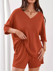 Orange-red V-neck ribbed knit lounge set with cuffed sleeves and drawstring shorts.