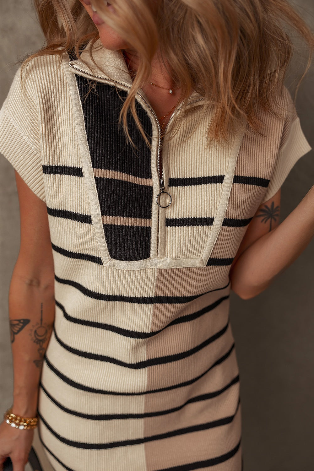 Colorblock ribbed mini dress with zip-neck and short sleeves in beige and black stripes.