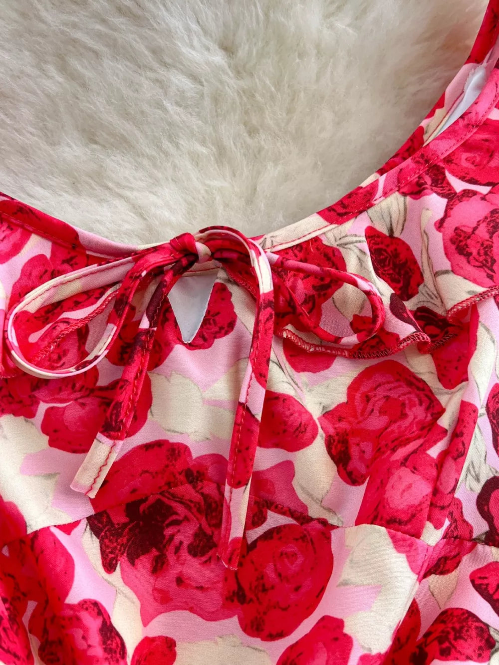 Floral ruffle trim mini dress with pink and red roses and a tie bow neckline.