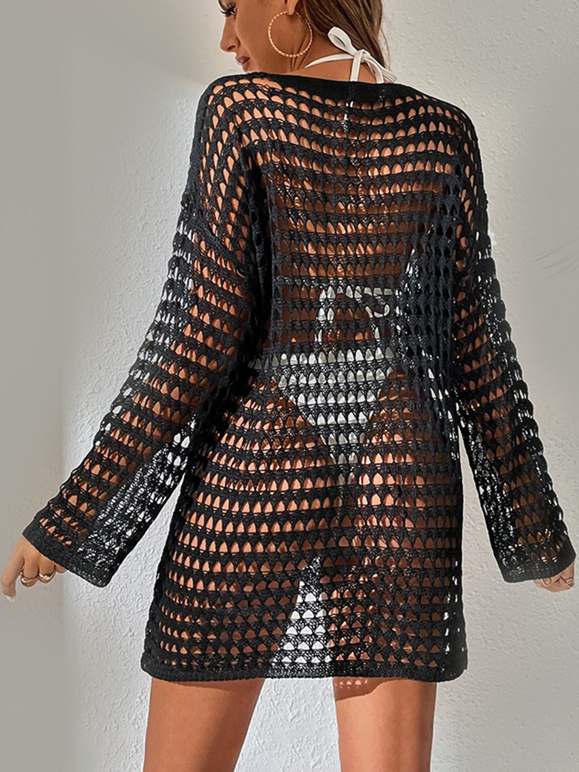 Black open-knit beach dress with long sleeves and boatneck, worn over swimwear.