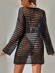 Black open-knit beach dress with long sleeves and boatneck, worn over swimwear.
