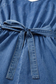 Medium wash denim romper with tie waist and ruffled hem detail