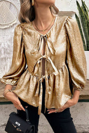 Gold peplum blouse with puff sleeves and a tie-front neckline.