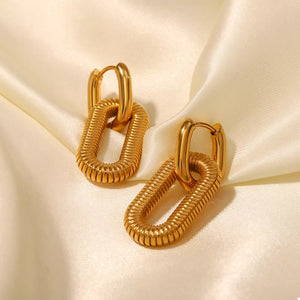 Gold link drop earrings with ribbed oval links on a satin background.