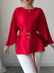 Red belted blouse with batwing sleeves and gold buckle detail, styled with white pants.