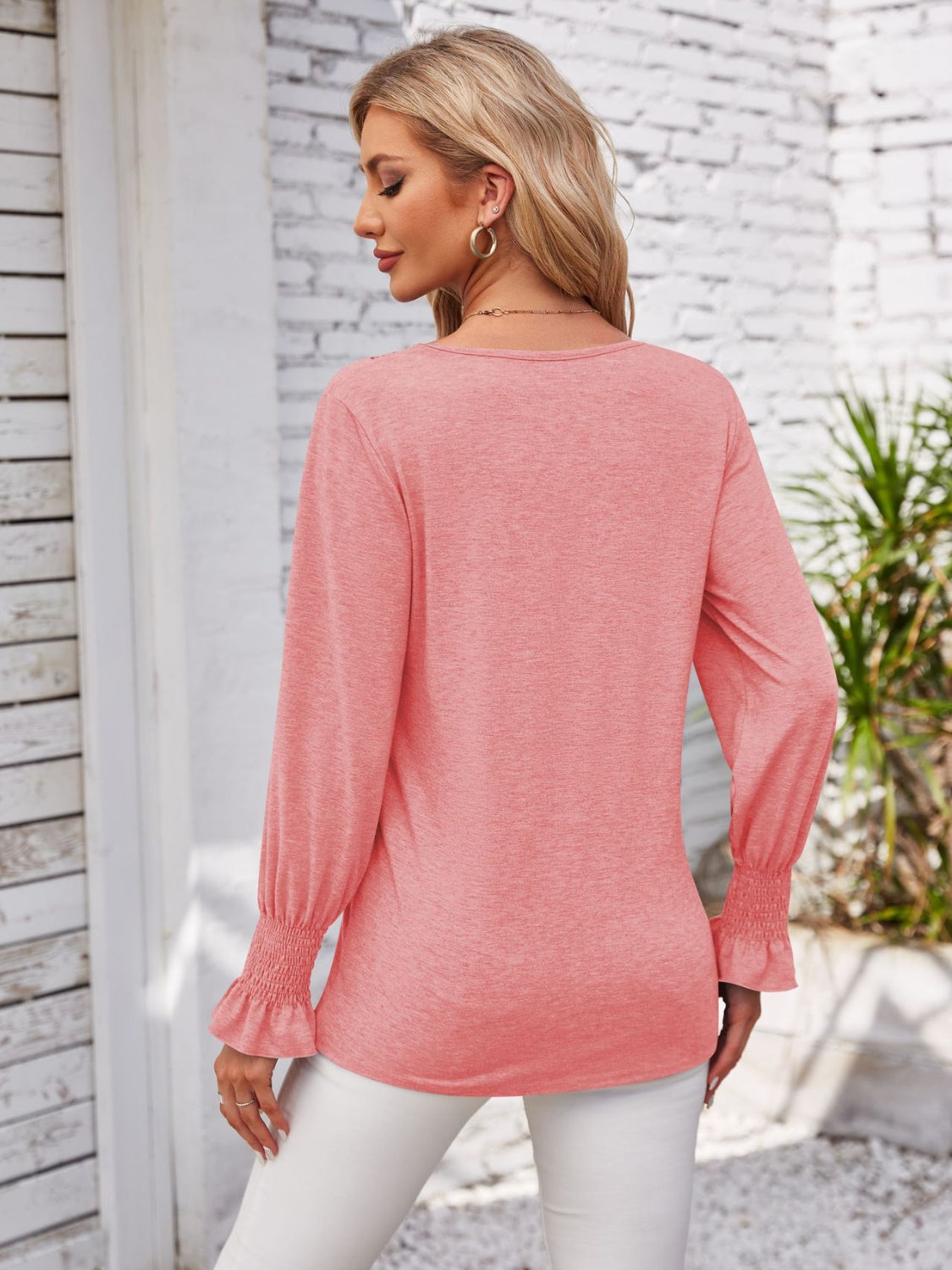 Coral blouson sleeve top with smocked cuffs and V-neck detail.