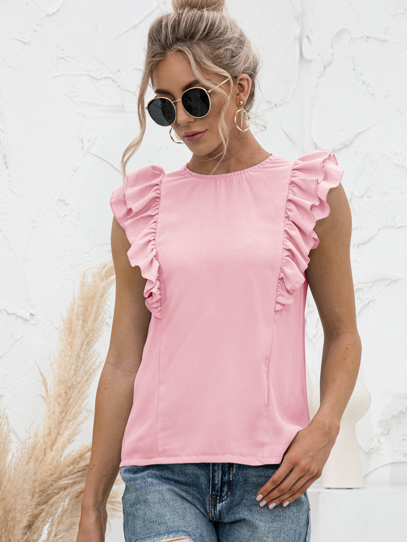 Blush pink ruffled yoke sleeveless blouse with a round neckline.
