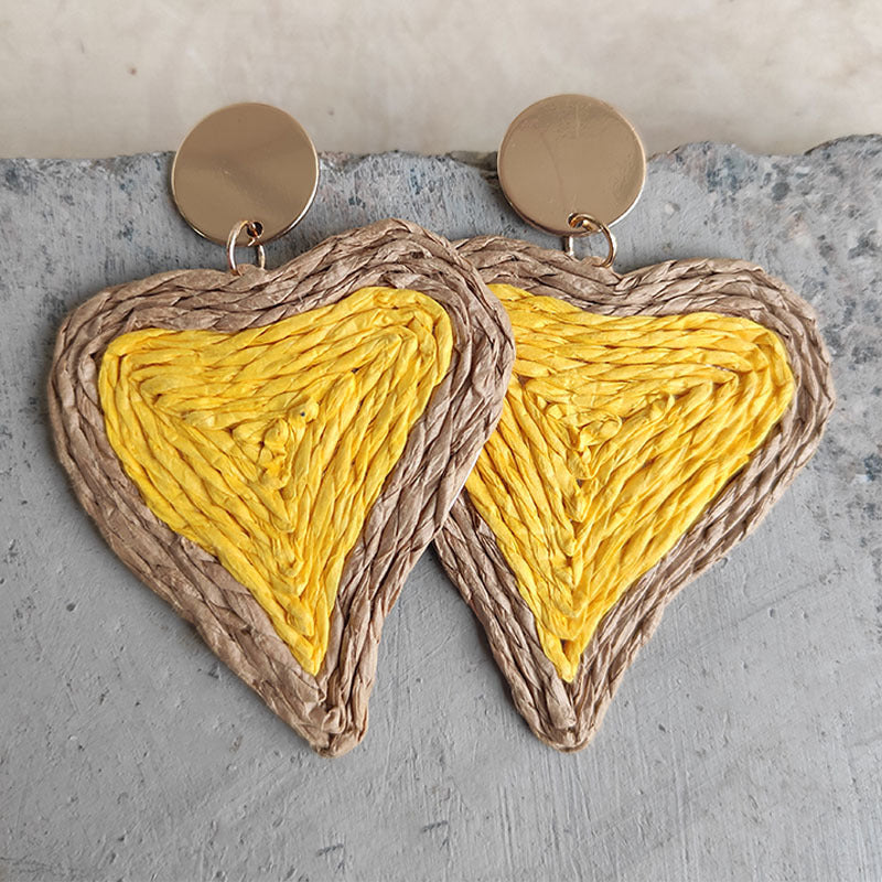 Yellow woven heart statement earrings with natural raffia trim and gold studs.