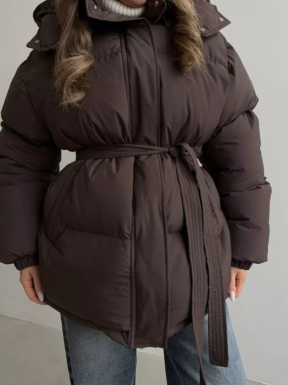 Dark brown belted puffer trench coat with hood and quilted detail.