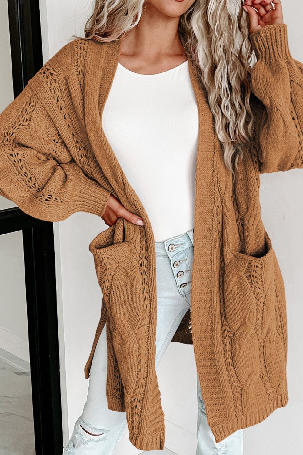 Camel cable knit open-front cardigan with pockets and openwork detail.
