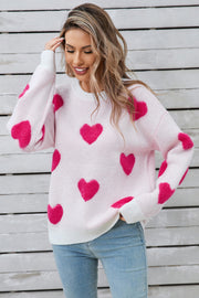 White crewneck sweater with allover hot pink heart appliqué and ribbed cuffs.