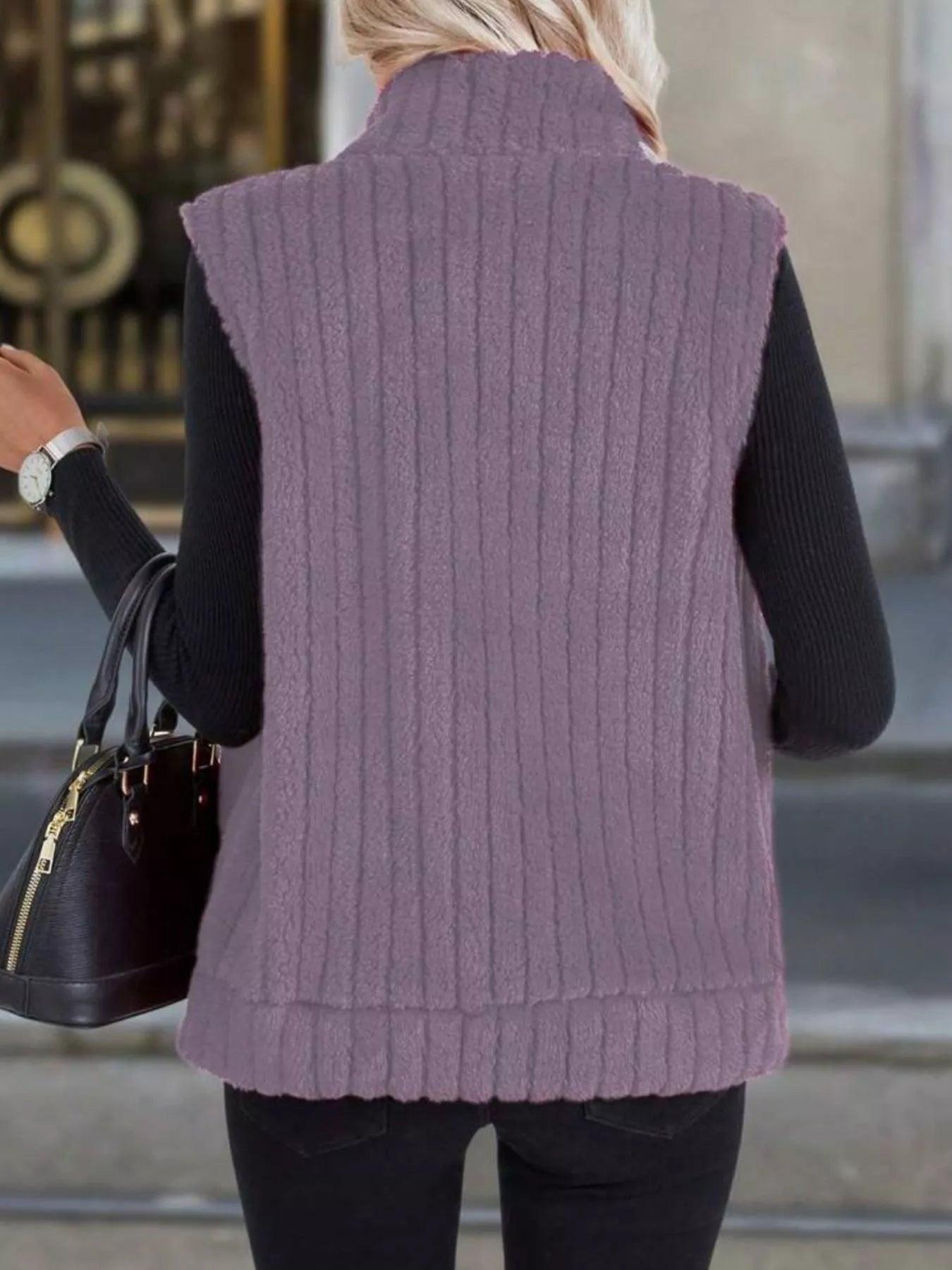 Purple fleece zip-up vest with ribbed texture and mock neck, worn over a black long-sleeve shirt.