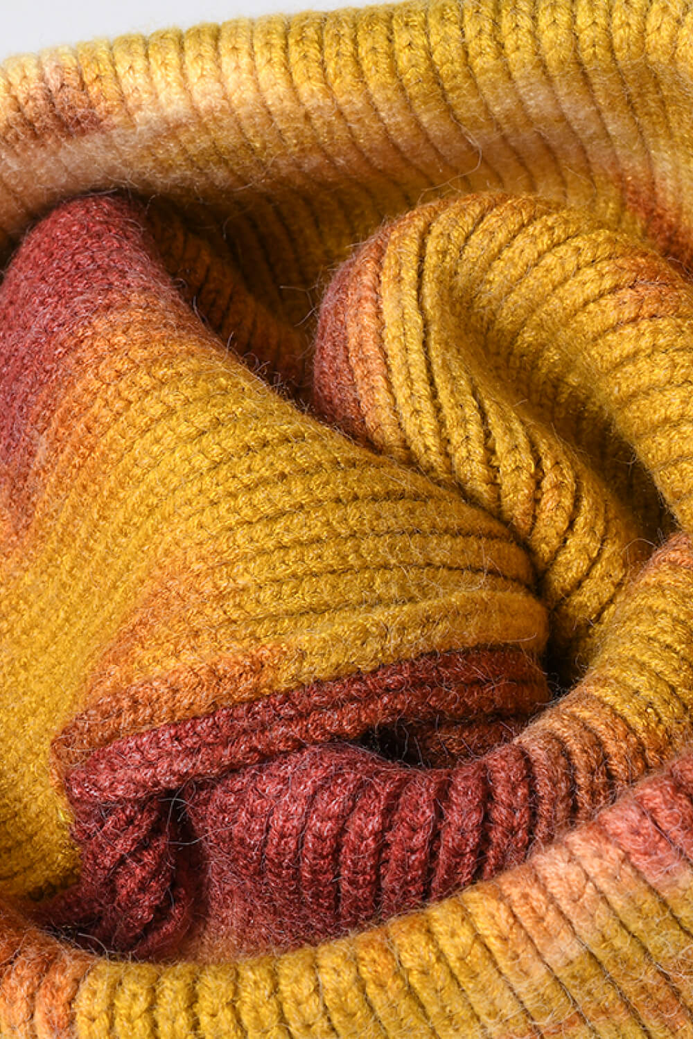 Ribbed knit beanie with a sunset dip-dye pattern in yellow, orange, and red tones.