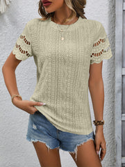 Beige eyelet blouse with scalloped short sleeves and intricate patterned fabric.