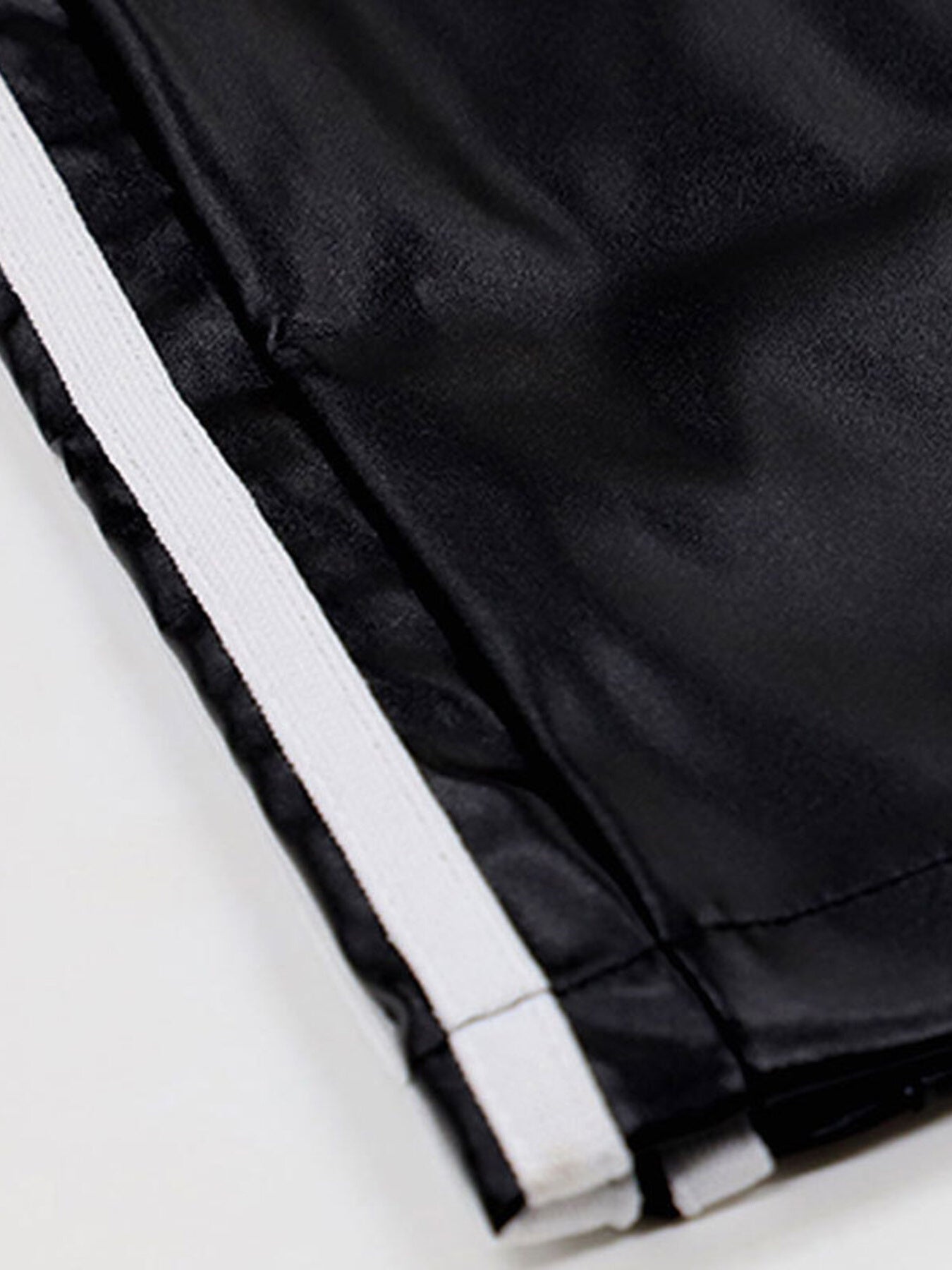 Black faux leather wide leg track pants with white side stripes and elastic waistband.