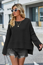 Black acrylic knit sweater with flared sleeves and slit hem detail.