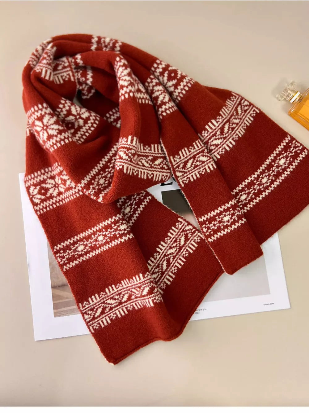 Reversible wool blend scarf in orange red with white snowflake and geometric patterns.