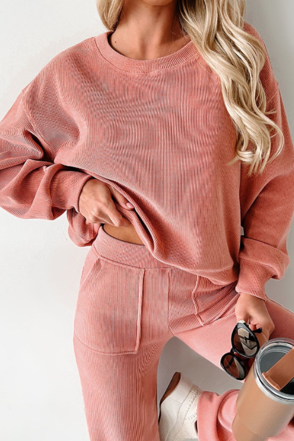 Pink corduroy lounge set with relaxed fit sweatshirt and pants, featuring ribbed texture and pockets.