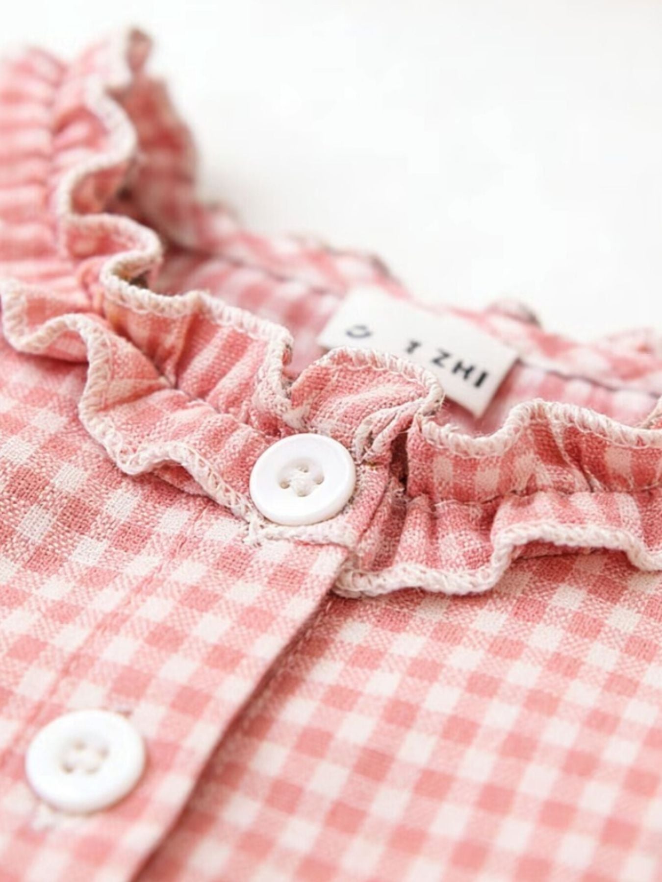 Blush pink gingham baby dress with ruffled neckline and button detail