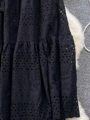 Black eyelet tiered maxi skirt with cutout details and ruffled tiers.