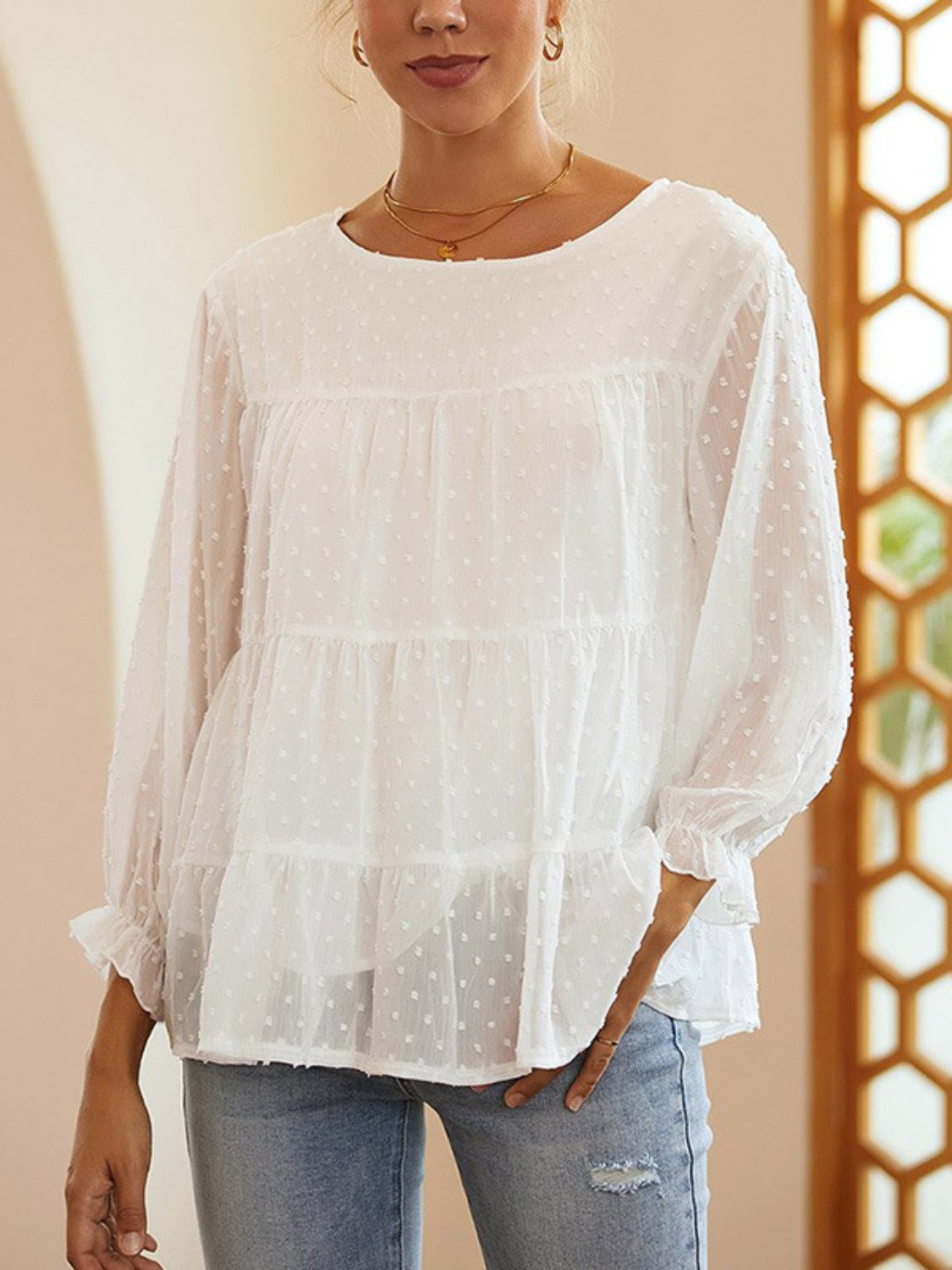 White tiered Swiss dot peasant blouse with ruffled cuffs and a round neckline.