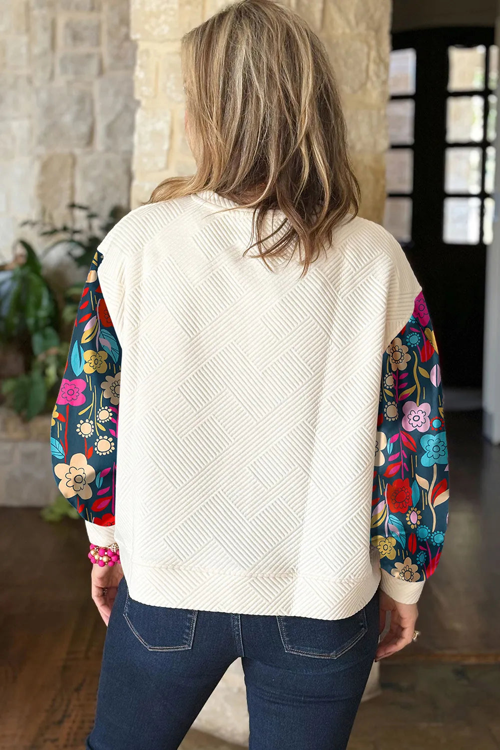 Ivory quilted knit top with colorful floral print sleeves.