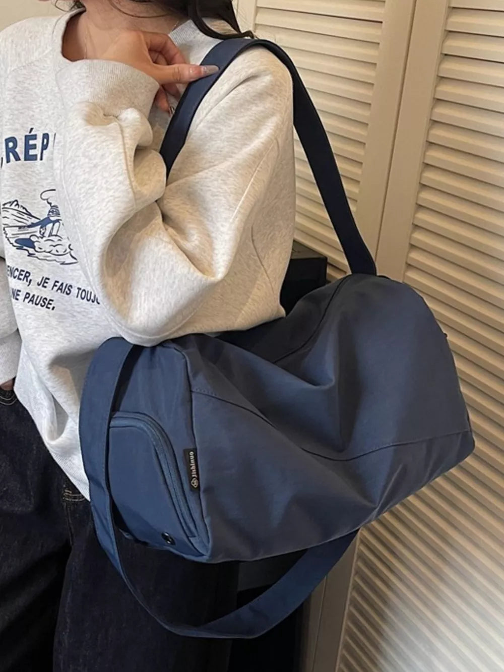 Casual large blue Oxford cloth travel bag with adjustable strap and front pocket.