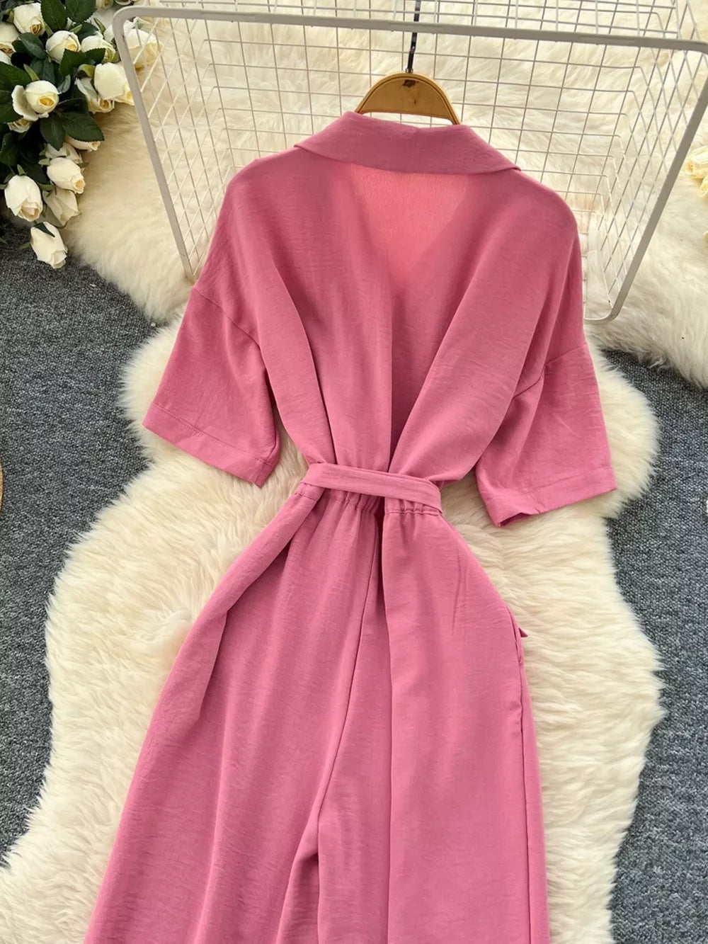 Pink belted wide-leg maternity jumpsuit with pockets and short sleeves.