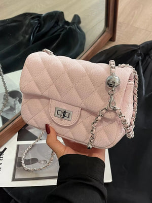 Pink quilted chain crossbody clutch bag with silver hardware and a decorative ball charm.