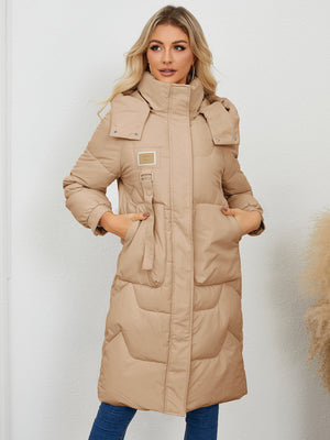 Camel quilted puffer parka with buckle detail and hood, full length.