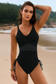 Black cross-front mesh panel one-piece swimsuit with ruched sides and tie details.