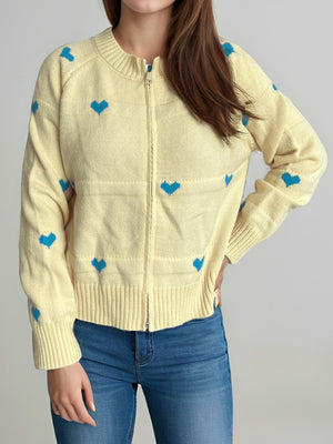 Pastel yellow zip-through knit cardigan with blue heart appliqué and ribbed cuffs.