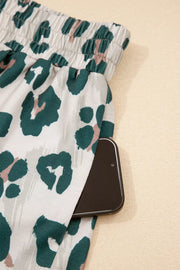 Pajama pants with leopard print and a side pocket holding a phone.