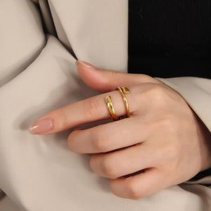 Gold sculptural spiral steel ring with a modern, open design.