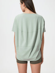 Relaxed fit performance tee in light green with curved seam details on back.