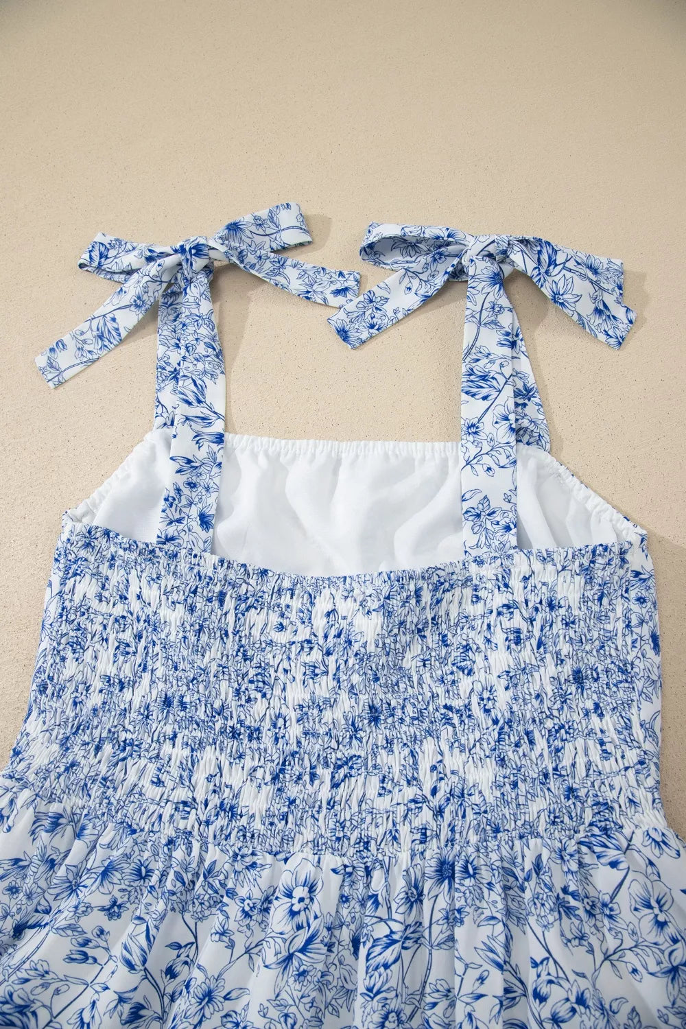 Maxi dress with blue floral print, smocked bodice, and tie-strap shoulders.